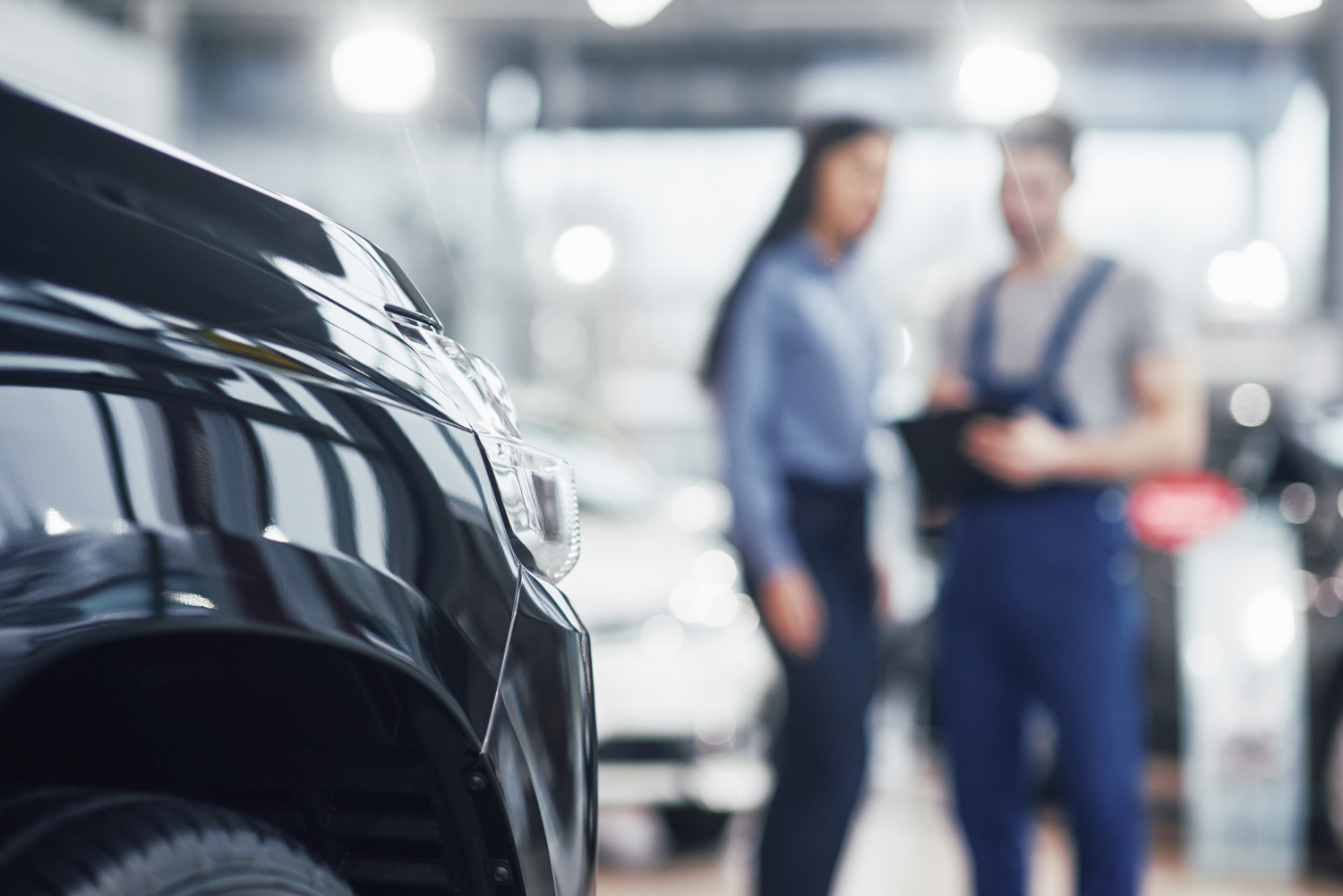 beautiful-young-woman-is-talking-handsome-car-mechanic-while-repair-car-dealership
